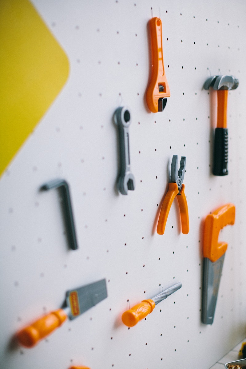 Orange and Gray Plastic Toy Tools on a White Pegboard